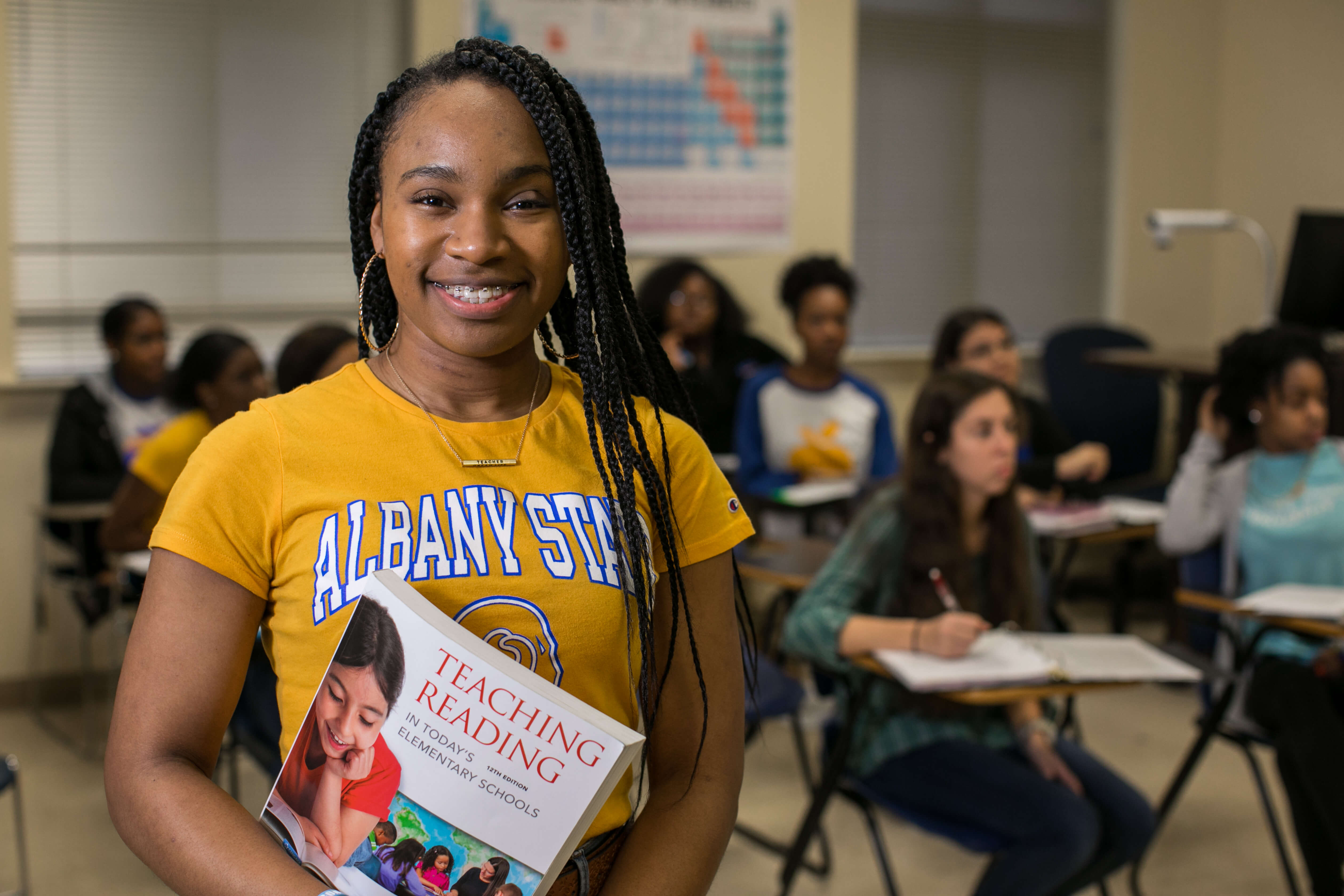 Student smiling while holding a book on teaching.