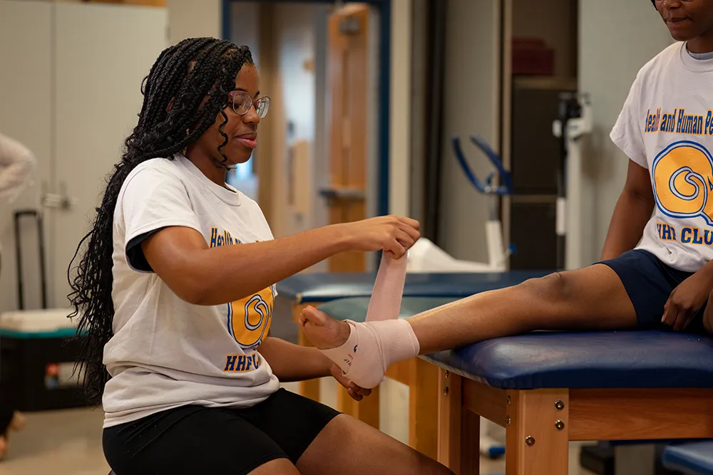 Student applying bandage on foot and ankle